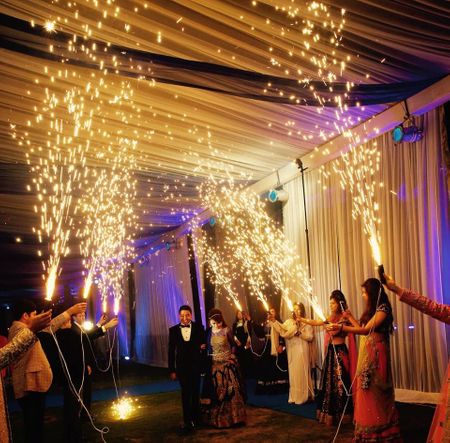Photo of Bride and Groom Entering with Guests Holding Cold Pyro