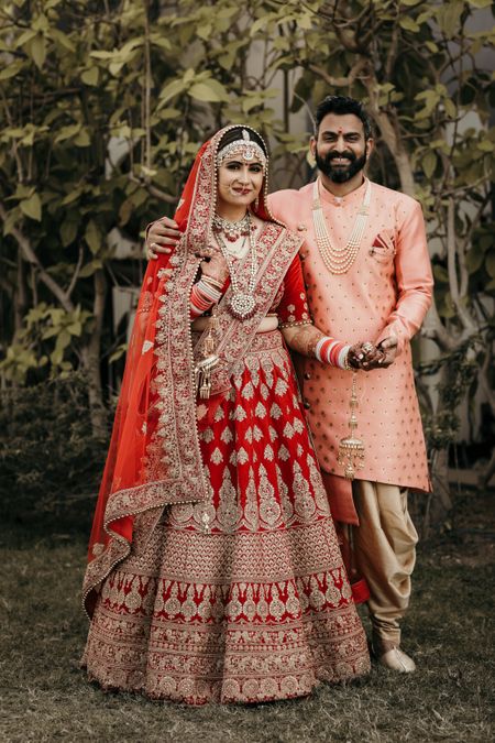 Contrasting bride and groom outfits in red and peach 