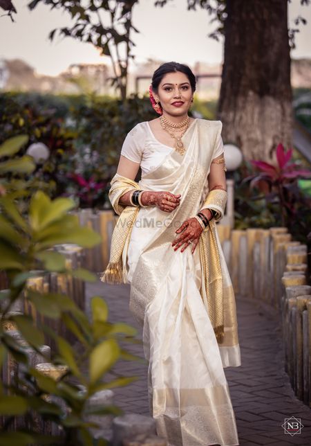 Bride wearing an ivory saree with a matching banarsi dupatta.