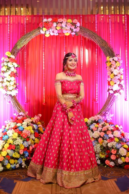 Photo of A bride in a  bright pink off shoulder outfit for her mehendi