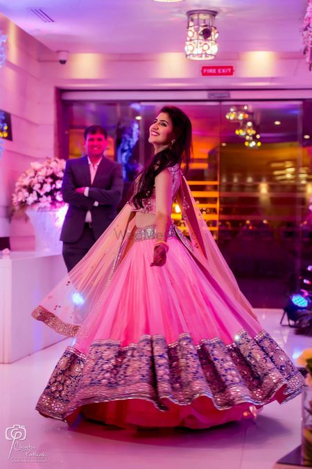 Bride twirling in light pink and blue net lehenga