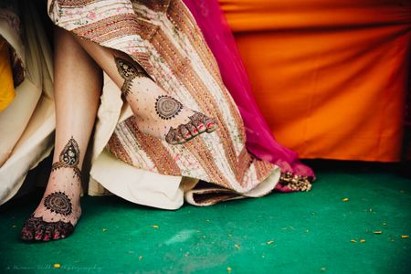 Bride sitting cross legged showing mehendi on feet