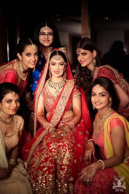 Photo of Bride in red and gold lehenga with bridesmaids