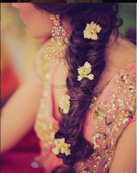 Mehendi hairstyle with side braid and flowers