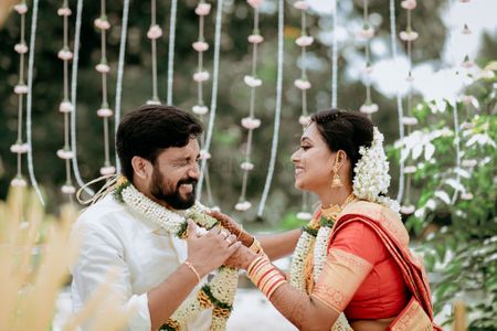Photo of cute south indian couple portrait against floral string backdrop