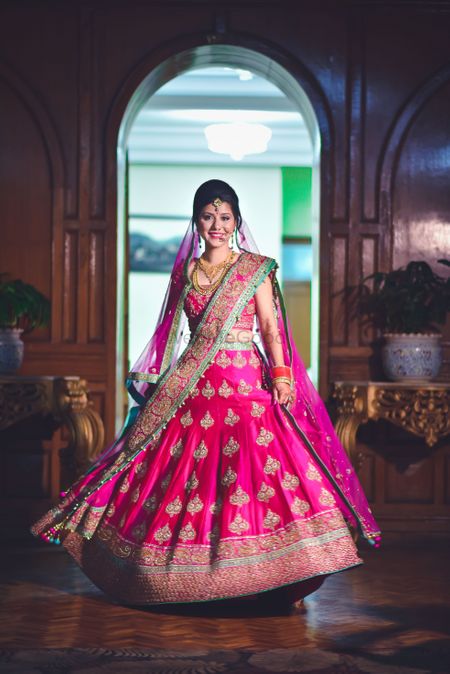 Photo of Bride twirling in red lehenga with gold motifs