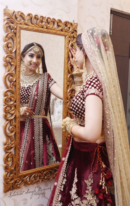 Photo of Bride in marsala and gold lehenga staring at mirror