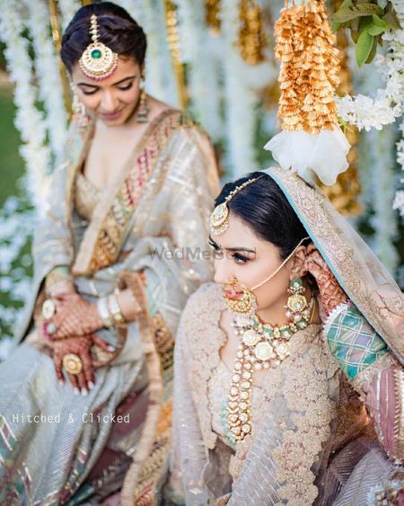 Photo of wedding day bridal portrait with her sister while adjusting jewellery