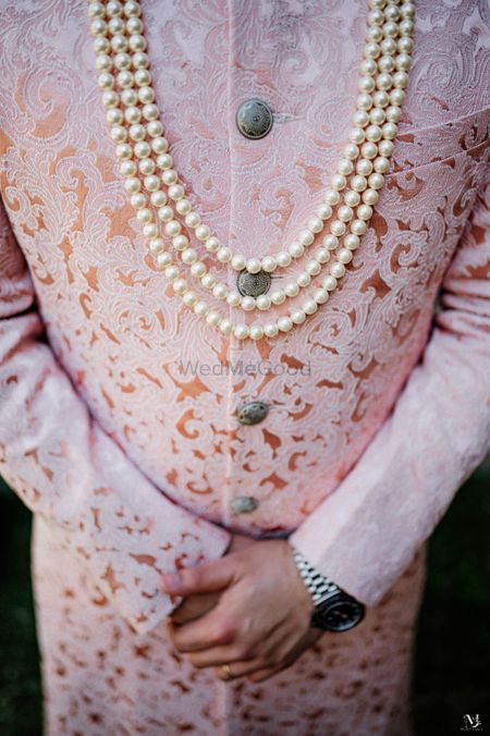 Groom wearing textured sherwani with a pearl mala.