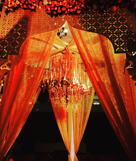Unique mandap decor in orange and gold with hanging gota strings