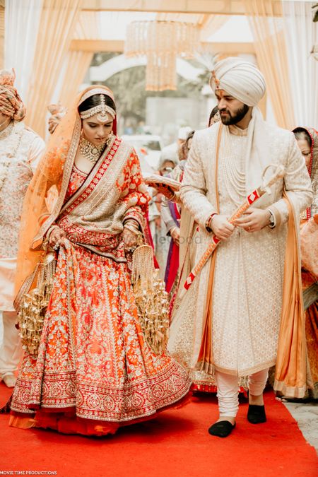 sikh couple on anand karaj with the bride in an orange lehenga