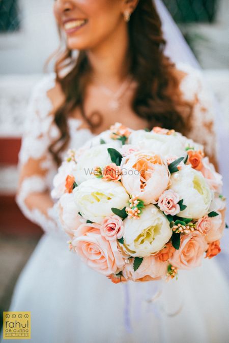 Bride holding a pastel-hued floral bouquet.
