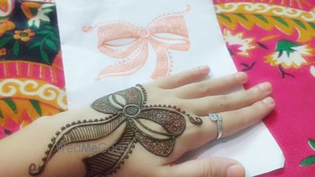 Bow shaped mehendi on back of the hand