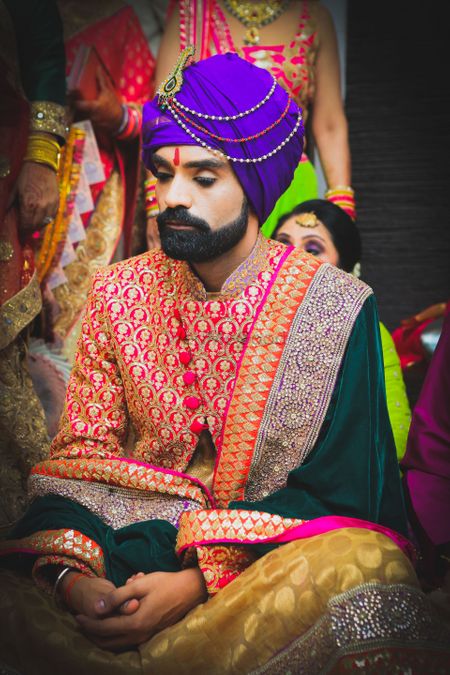 Colourful groom outfit with purple safa and velvet dupatta