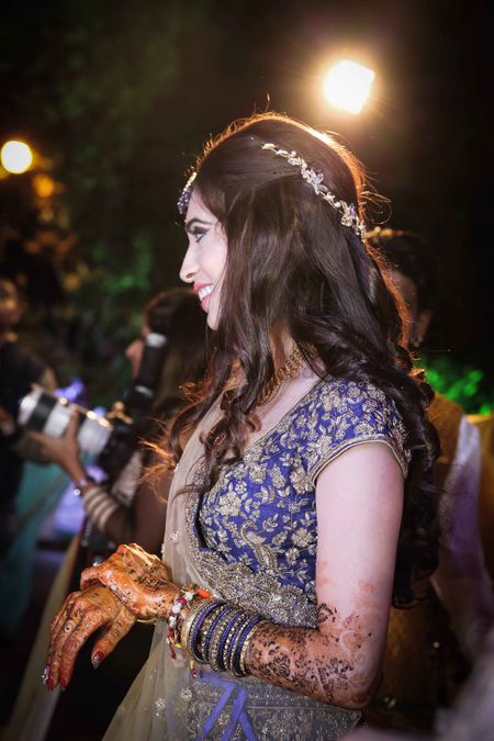 Wavy hairstyle with floral band for bride on sangeet