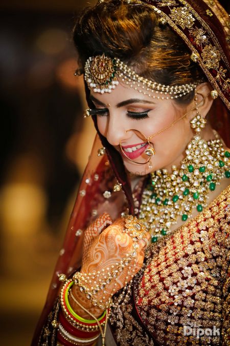 Bride wearing necklace with green beads and pearl maangtikka