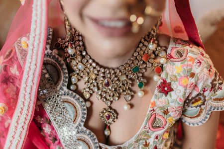 Bride wearing a navaratna necklace with a scalloped blouse.