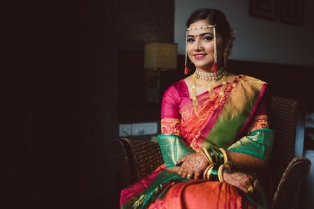 A marathi bride dressed in pink and orange saree along with green sheela