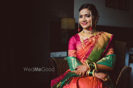 A marathi bride dressed in pink and orange saree along with green sheela