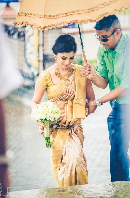 South Indian bride entering under matching umbrella