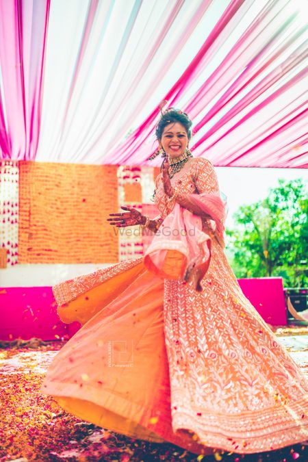 Happy bride twirling in orange lehenga shot