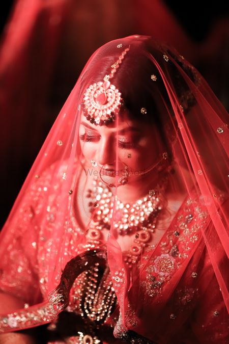 Photo of bride with red dupatta as veil shot on wedding day