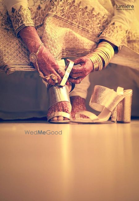 Bride tying her silvr wedge heels
