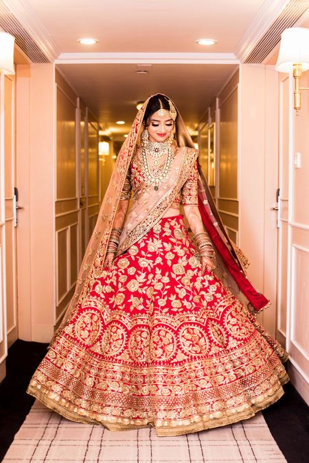Bride showing off red and gold bridal lehenga