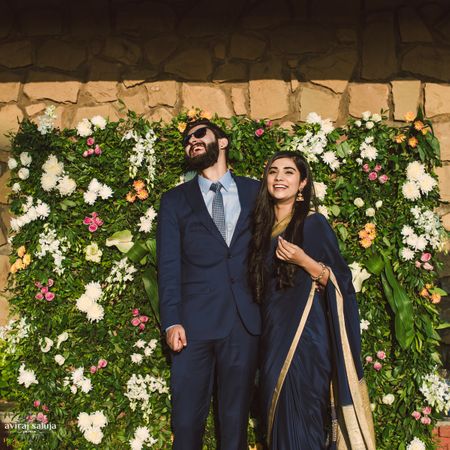 Engagement decor idea with couple standing against flower wall