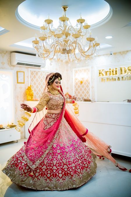 Photo of Bride twirling in red and pink ombre lehenga