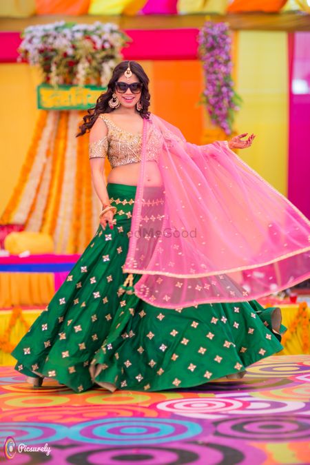 Bride dancing wearing green and pink lehengas on mehendi