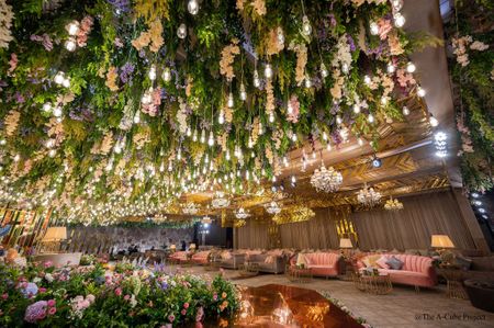 Photo of Lush greens, suspended bulbs and florals for the ceiling decor.