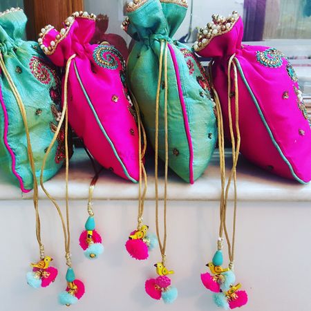 Colourful potlis with pompoms as mehendi giveaways