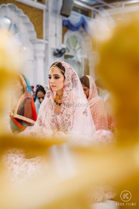 Candid shot of a Sikh bride dressed in a pink lehenga. 