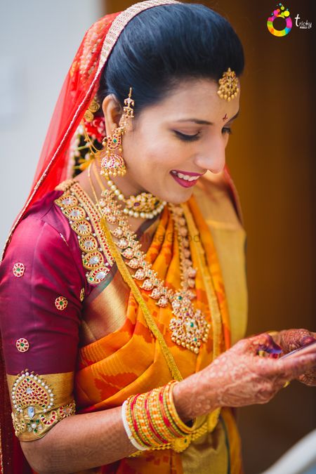 South Indian bride wearing orange kanjivaram with embellished maroon blouse