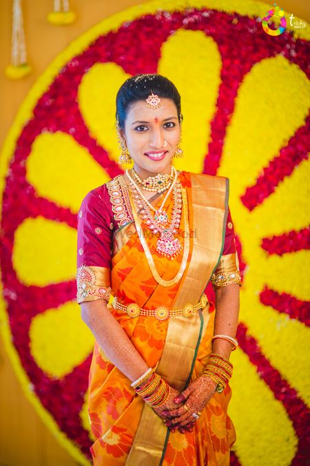 South Indian bride wearing orange and gold kanjivaram saree