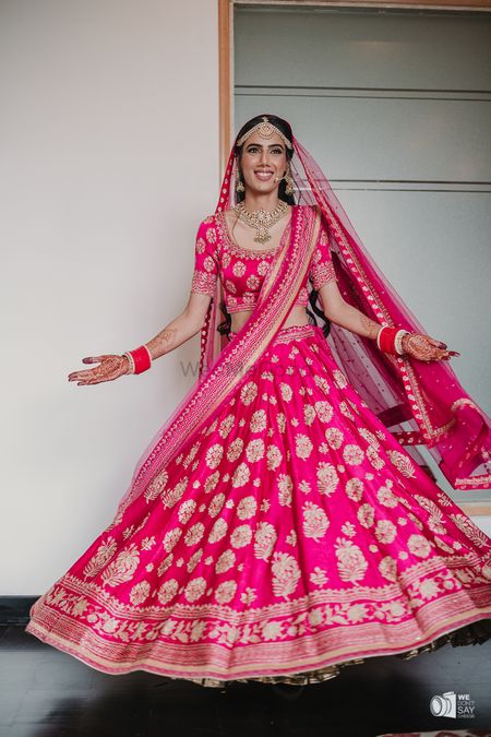 Photo of Bride twirling in a pink lehenga.