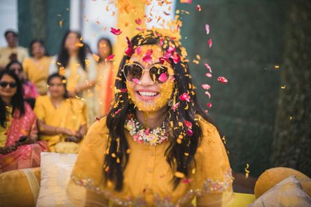 Photo of petal shower haldi photo with bride in yellow