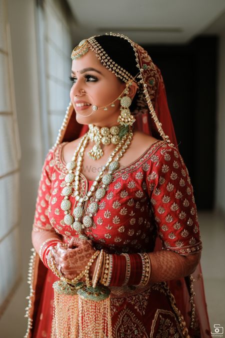 Bride dressed in red lehenga with contrasting jewellery.
