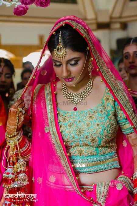 Bride in Aqua and Bright Pink Lehenga with Gold Motifs