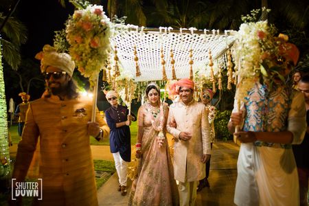 Bride entering under unique phoolon ki chadar with kaleere