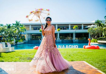 Bride wearing pink net gown holding floral lace umbrella