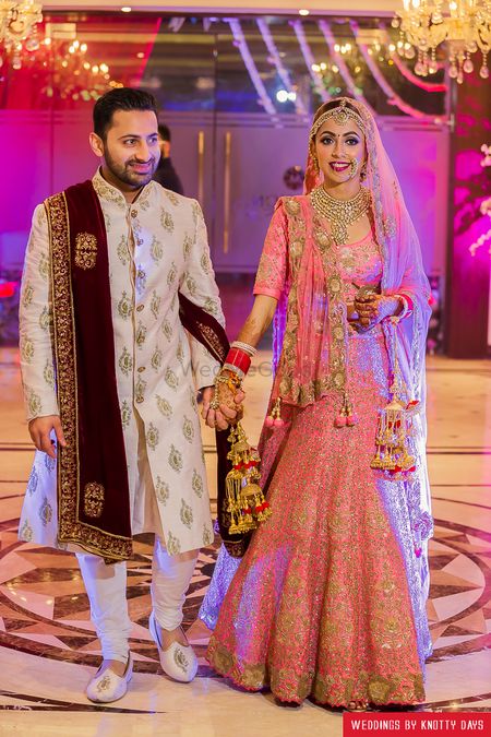 Bride in coral lehenga with gold sequin work and pink kaleere