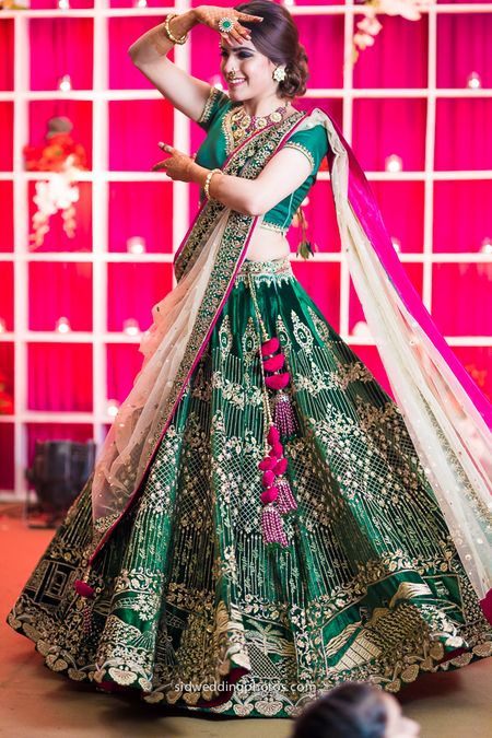 Photo of Emerald green lehenga with red tassels and contrasting dupatta