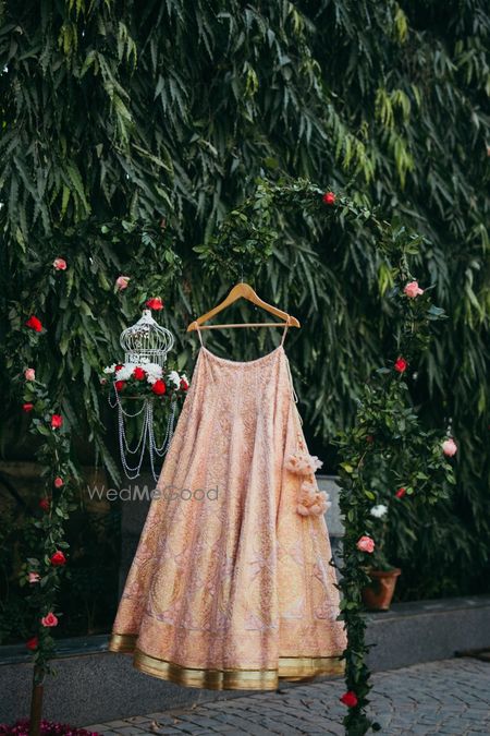 Peach threadwork lehenga on hanger with birdcage