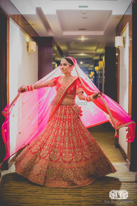 Bride twirling and posing with dupatta in red lehenga