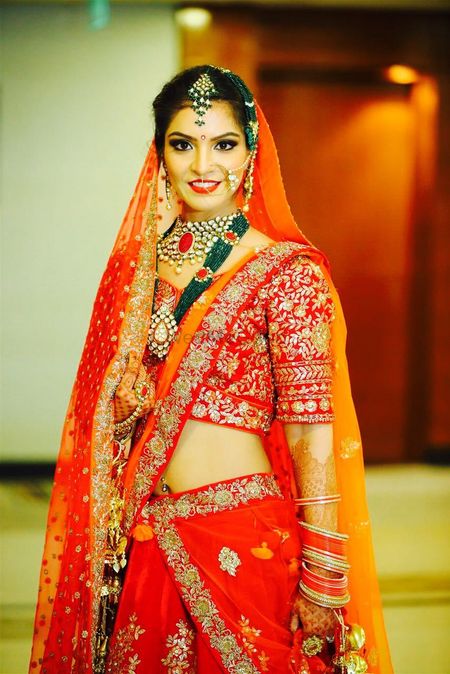 Red lehenga with contrasting jewellery with green beads