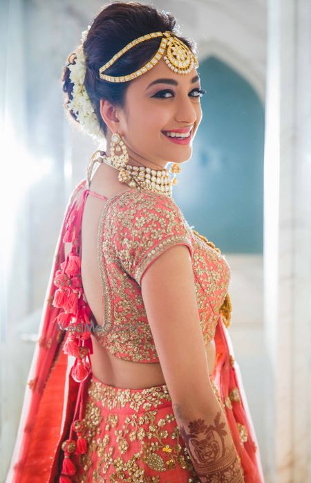 Happy bride in coral lehenga looking back shot 