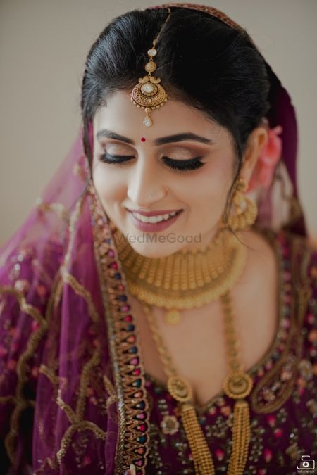 Bride wearing a deep pink lehenga with gold jewellery.