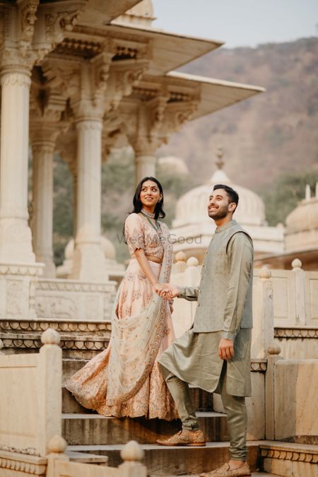 Bride and groom posing against a royal palace.